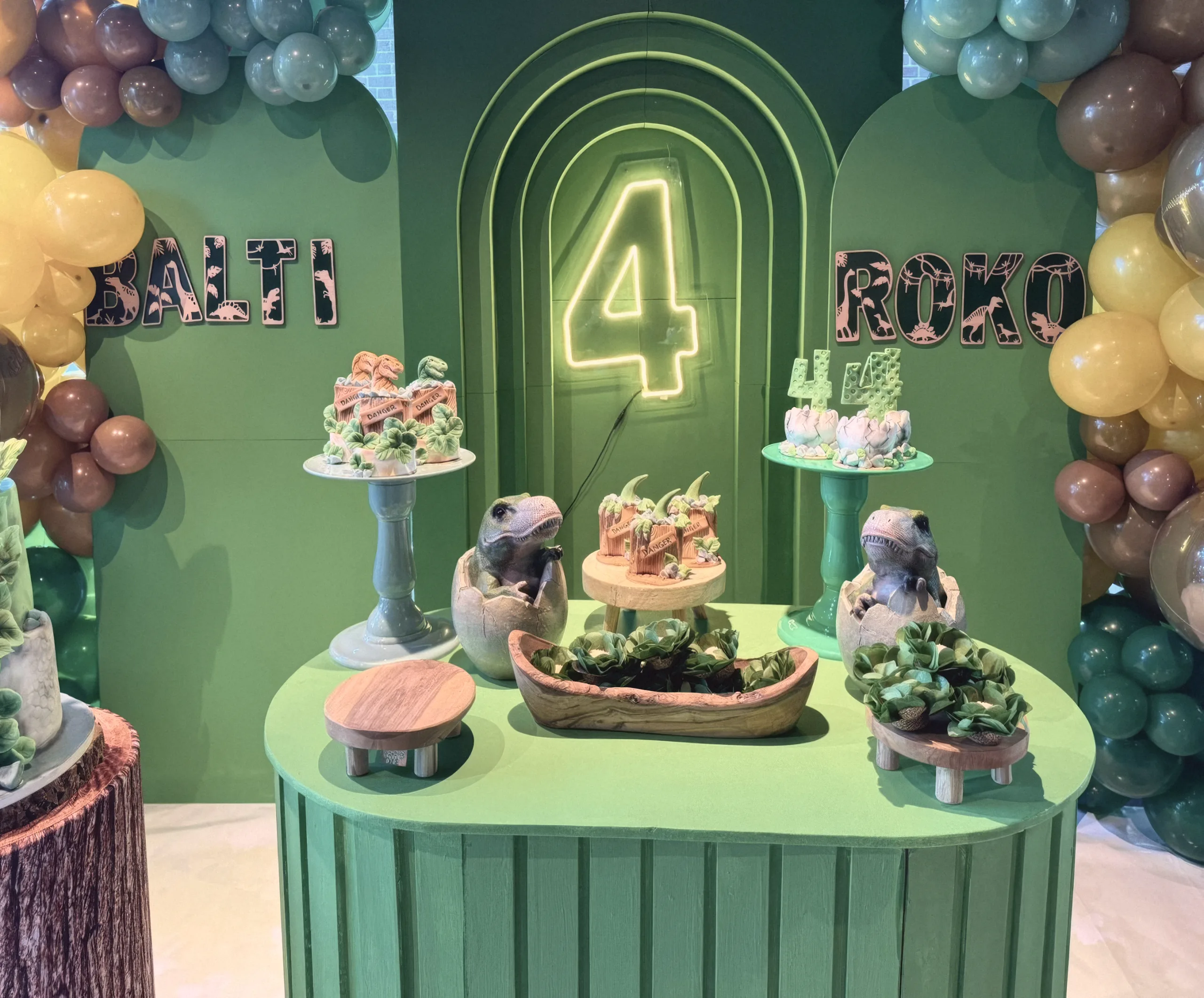 The dinosaur dessert table under a neon number four