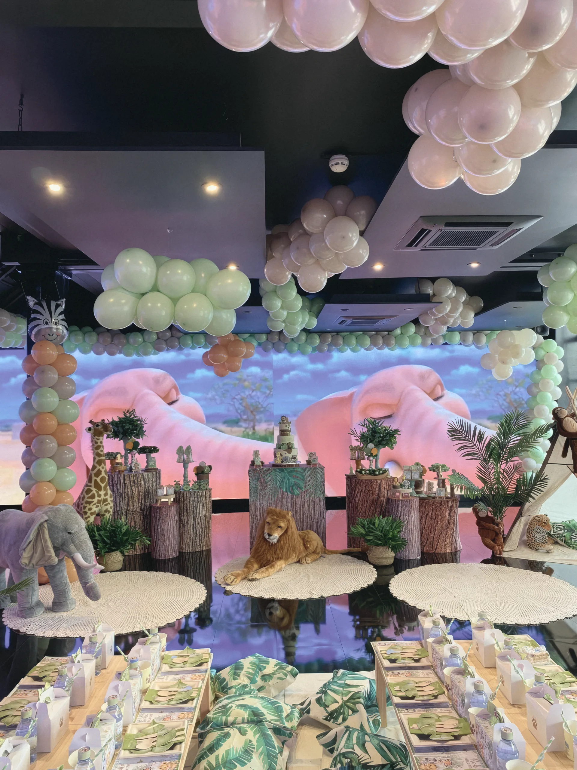 The safari set: a lion, giraffes and tree-trunk stands in front of the screen wall